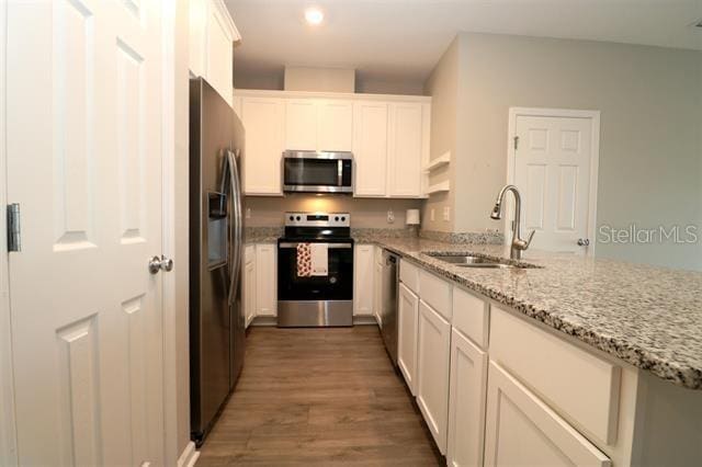 kitchen featuring sink, dark wood-type flooring, white cabinetry, stainless steel appliances, and light stone countertops