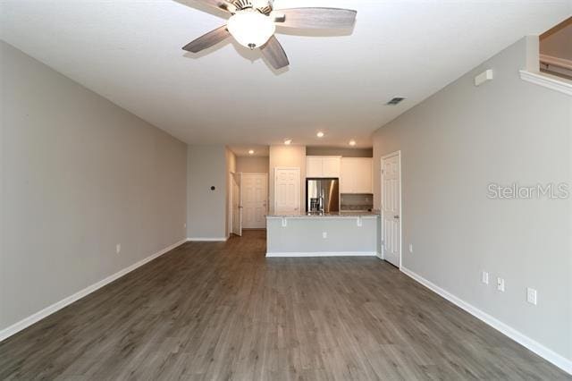 unfurnished living room with dark hardwood / wood-style flooring and ceiling fan