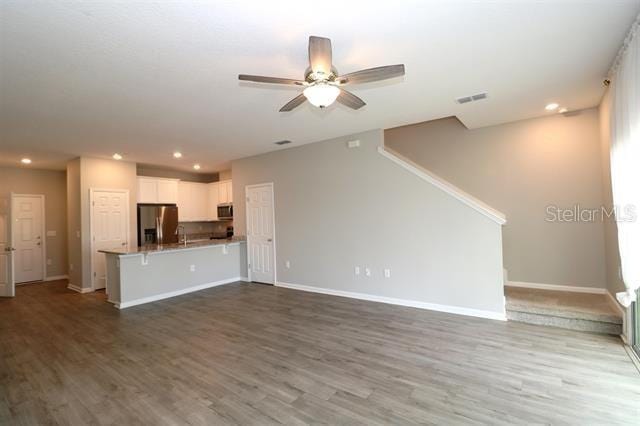 unfurnished living room with ceiling fan and hardwood / wood-style floors