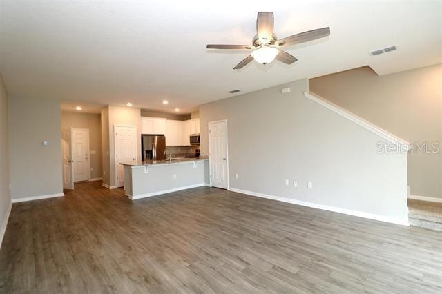 unfurnished living room featuring hardwood / wood-style flooring and ceiling fan