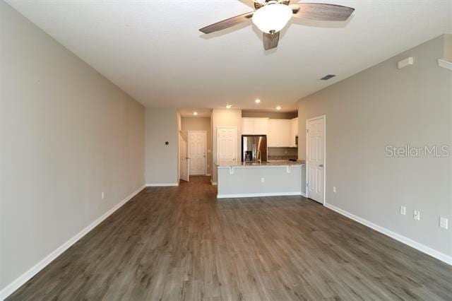 unfurnished living room with ceiling fan and dark hardwood / wood-style floors