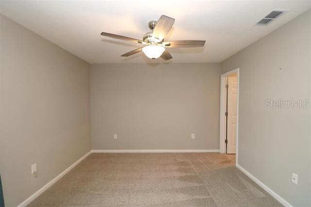 carpeted spare room featuring ceiling fan