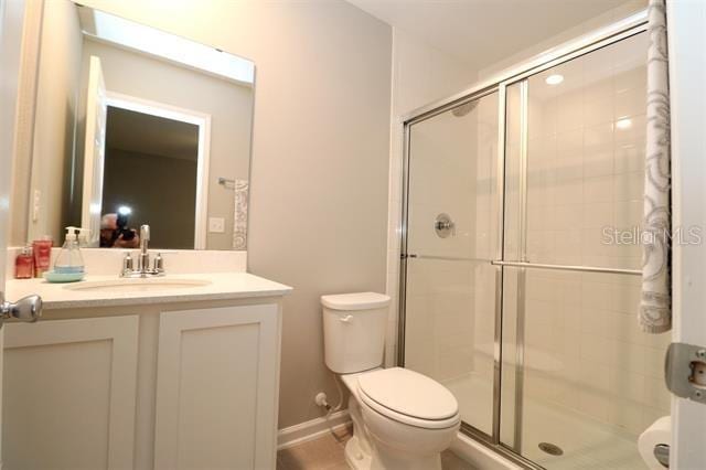 bathroom featuring a shower with door, vanity, and toilet