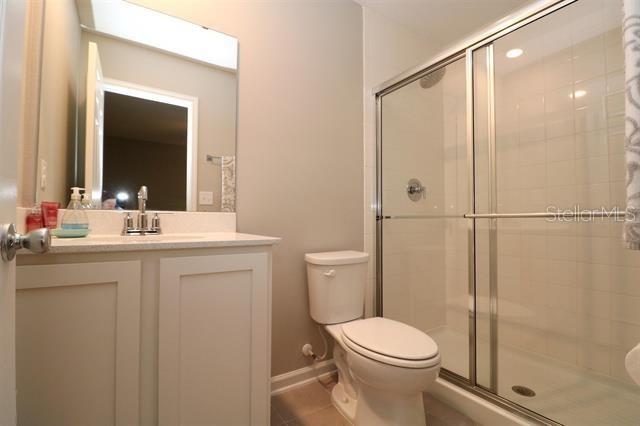 bathroom featuring tile patterned floors, vanity, toilet, and a shower with shower door