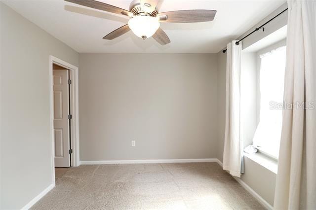 empty room featuring ceiling fan and light carpet