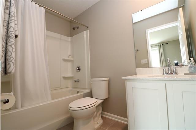 full bathroom featuring vanity, tile patterned floors, toilet, and shower / bathtub combination with curtain