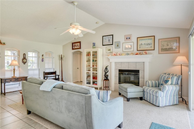 living room with a tile fireplace, lofted ceiling, light tile patterned floors, and ceiling fan