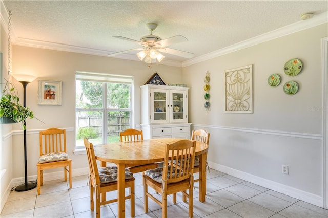 tiled dining room featuring ceiling fan, crown molding, and a textured ceiling