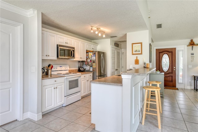 kitchen featuring light tile patterned flooring, white cabinetry, a breakfast bar area, kitchen peninsula, and stainless steel appliances