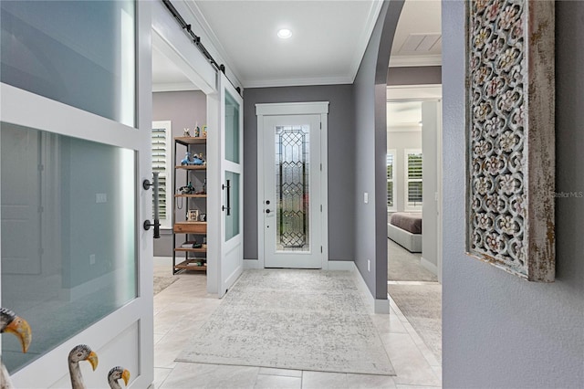 foyer entrance featuring a barn door, baseboards, and ornamental molding