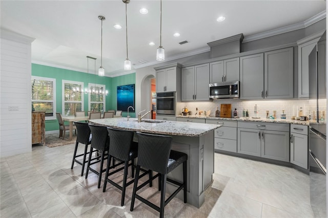 kitchen with visible vents, gray cabinets, arched walkways, appliances with stainless steel finishes, and light stone countertops