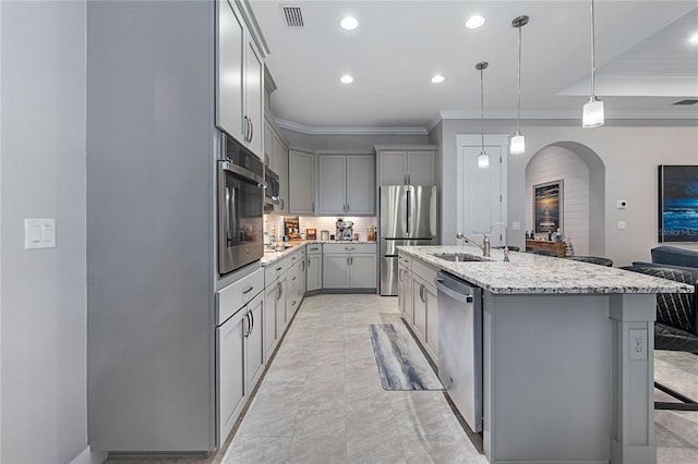 kitchen with ornamental molding, gray cabinets, a sink, stainless steel appliances, and arched walkways