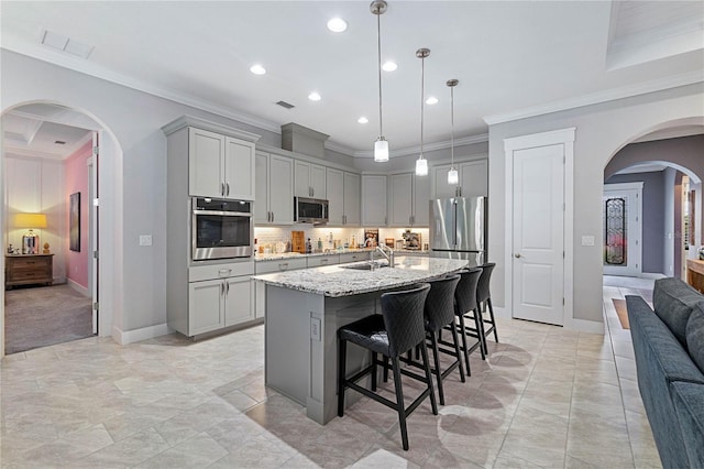 kitchen featuring visible vents, a breakfast bar, gray cabinets, arched walkways, and appliances with stainless steel finishes