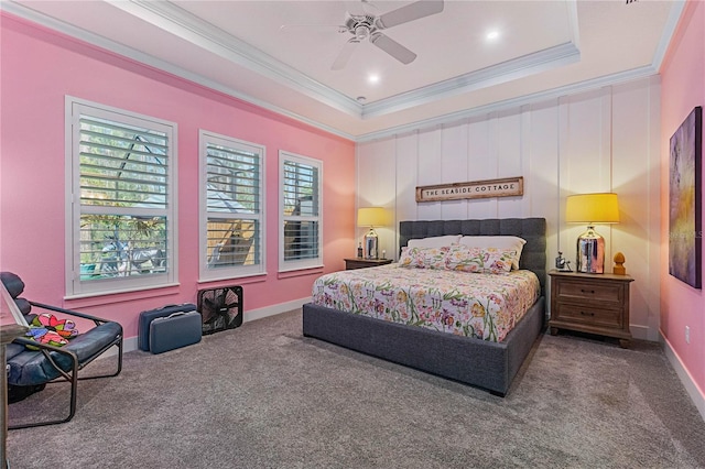 carpeted bedroom featuring a tray ceiling, baseboards, ornamental molding, and a ceiling fan