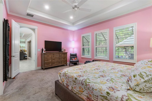 carpeted bedroom with a raised ceiling, a ceiling fan, visible vents, and ornamental molding