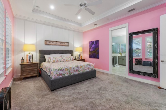 carpeted bedroom featuring visible vents, ensuite bath, a tray ceiling, and ornamental molding