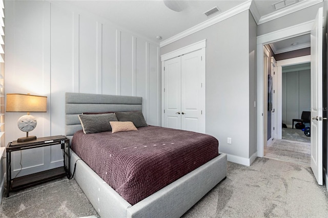 carpeted bedroom with visible vents, baseboards, a closet, and ornamental molding