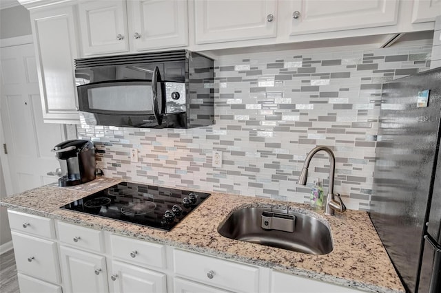 kitchen with tasteful backsplash, white cabinets, sink, and black appliances