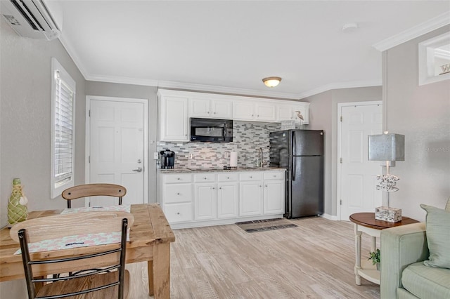 kitchen featuring white cabinetry, a wall mounted air conditioner, ornamental molding, light hardwood / wood-style floors, and black appliances