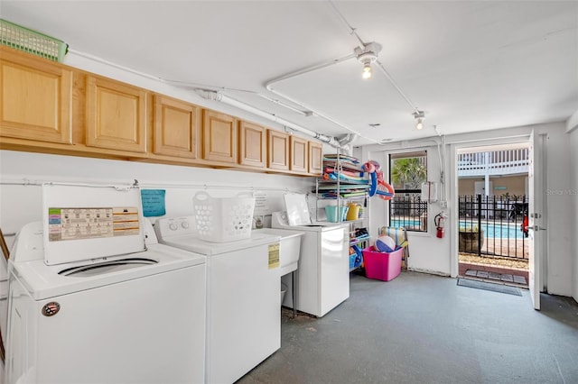 clothes washing area with cabinets, sink, and independent washer and dryer