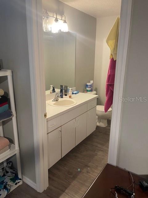 bathroom with hardwood / wood-style flooring, vanity, toilet, and a textured ceiling