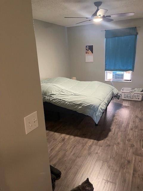 bedroom with wood-type flooring, ceiling fan, and a textured ceiling