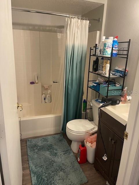 full bathroom featuring hardwood / wood-style flooring, vanity, shower / bath combination with curtain, and toilet