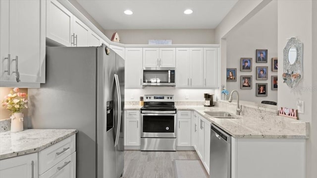 kitchen featuring white cabinetry, sink, light stone countertops, and appliances with stainless steel finishes