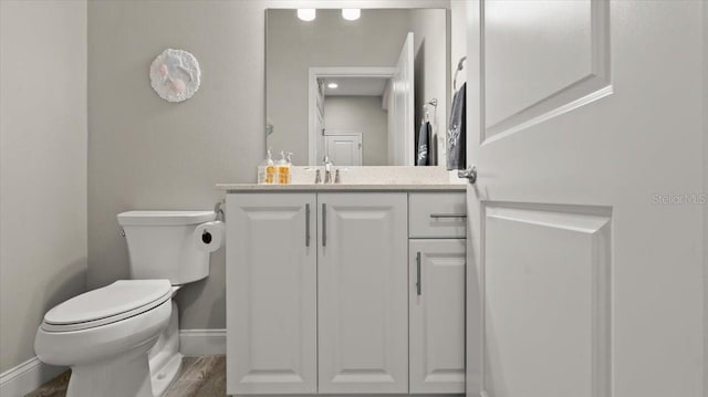 bathroom with hardwood / wood-style flooring, vanity, and toilet