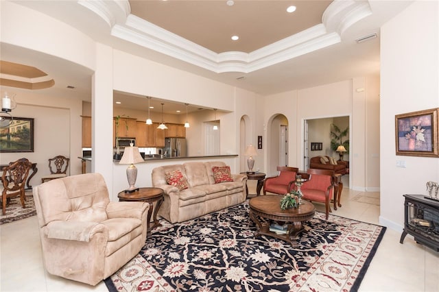 tiled living room with ornamental molding, a raised ceiling, and a wood stove