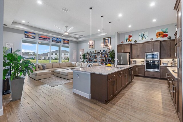 kitchen with appliances with stainless steel finishes, an island with sink, and dark brown cabinets