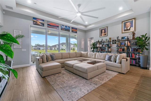 living room with hardwood / wood-style floors and a tray ceiling