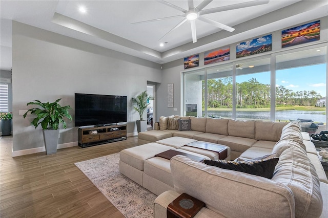 living room featuring ceiling fan, a raised ceiling, and hardwood / wood-style floors