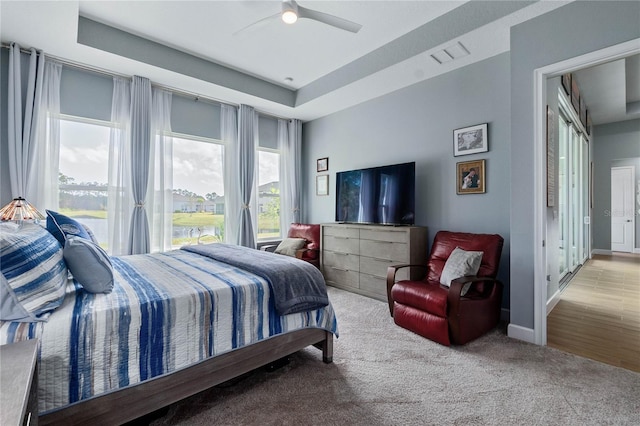 bedroom featuring light colored carpet, ceiling fan, and a tray ceiling