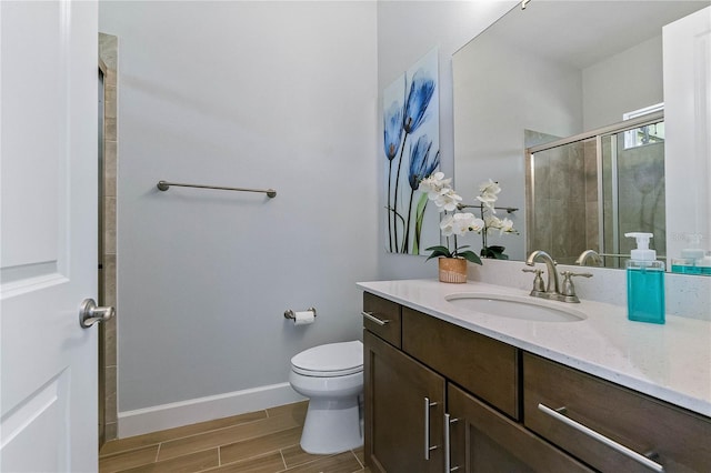 bathroom featuring vanity, a shower with shower door, and toilet