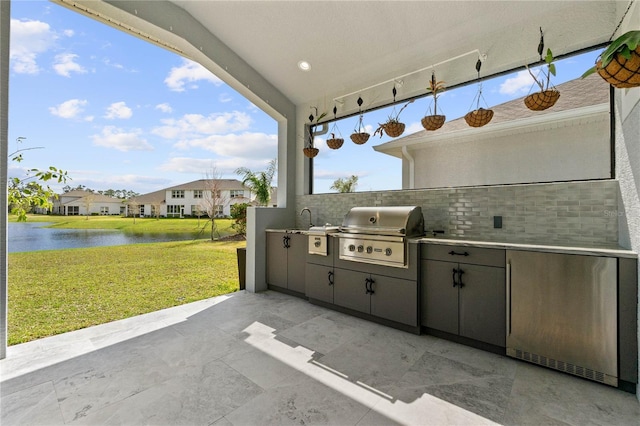 view of patio featuring exterior kitchen, a water view, and grilling area