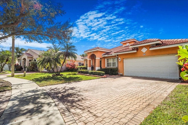 mediterranean / spanish house with a garage and a front lawn