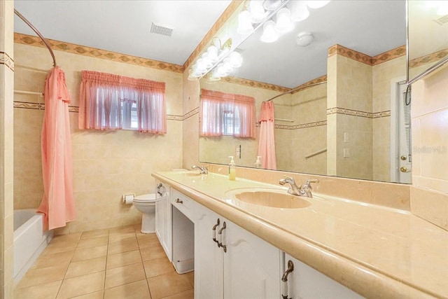 full bathroom featuring tile patterned floors, toilet, tile walls, vanity, and shower / bathtub combination with curtain