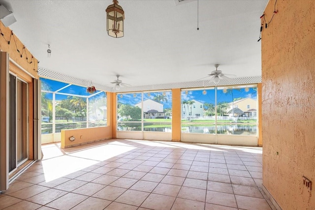 unfurnished sunroom with ceiling fan, a healthy amount of sunlight, and a water view