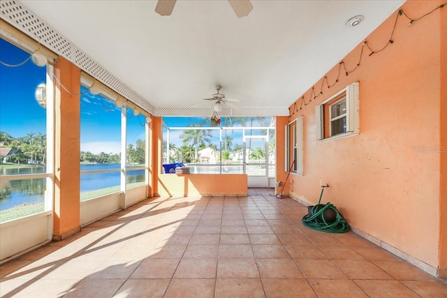 unfurnished sunroom with ceiling fan and a water view