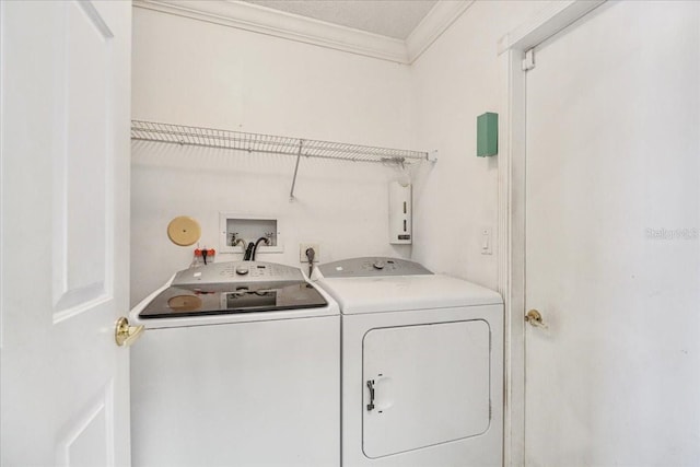 clothes washing area featuring crown molding and washing machine and clothes dryer