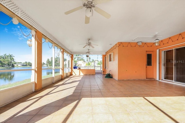 unfurnished sunroom featuring ceiling fan and a water view