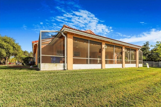 rear view of property featuring a yard and a sunroom