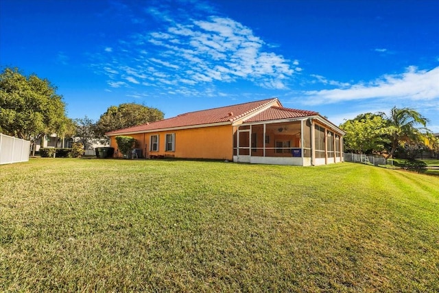 rear view of house featuring a sunroom and a lawn