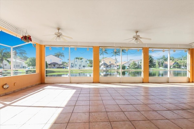 unfurnished sunroom featuring a water view and ceiling fan