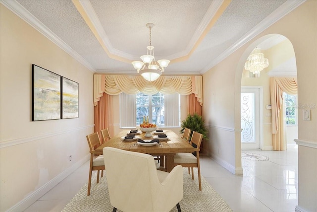 tiled dining room featuring a notable chandelier, ornamental molding, a raised ceiling, and a textured ceiling