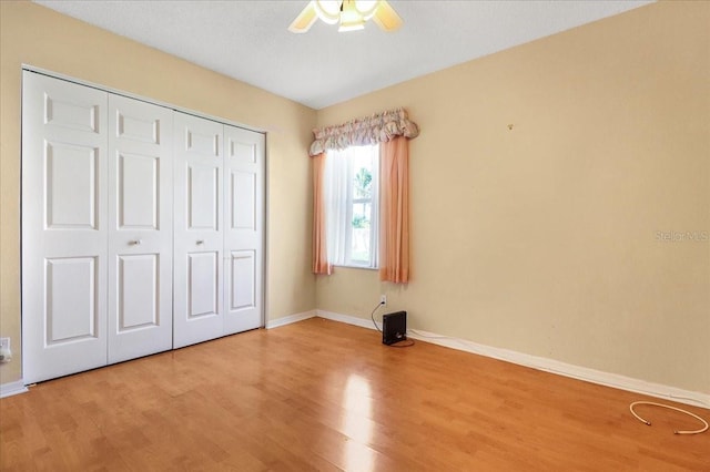 unfurnished bedroom with hardwood / wood-style floors, ceiling fan, and a closet