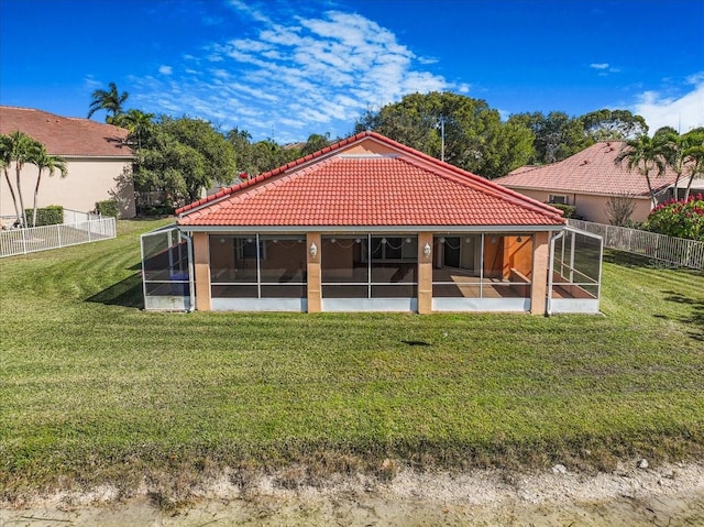 rear view of property featuring a sunroom and a lawn