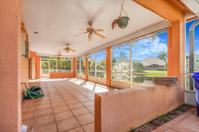 unfurnished sunroom featuring a water view and ceiling fan