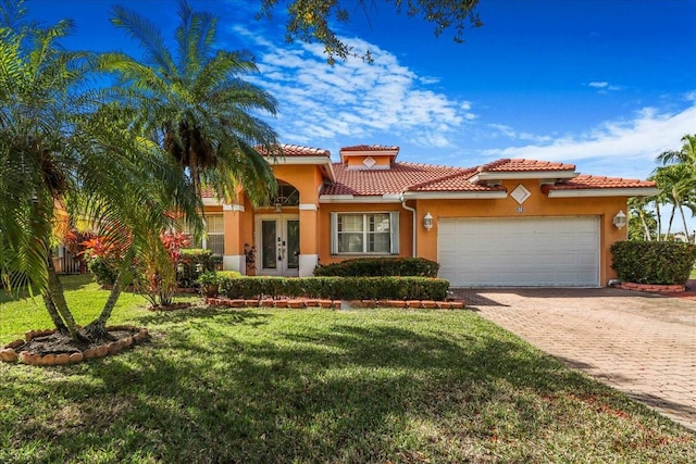 mediterranean / spanish-style home with a garage, a front yard, and french doors